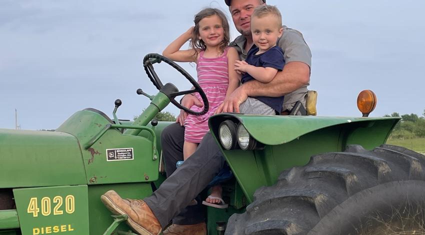 man on green tractor with small girl and boy