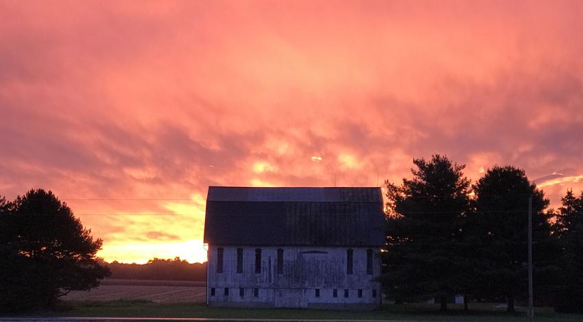 White barn with red sunset in background