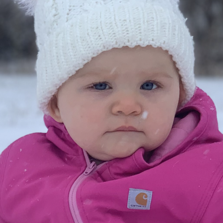 baby in pink snowsuit and white hat