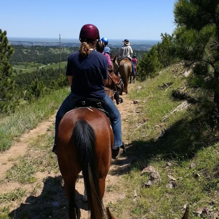 people on horseback on trail overlooking vista