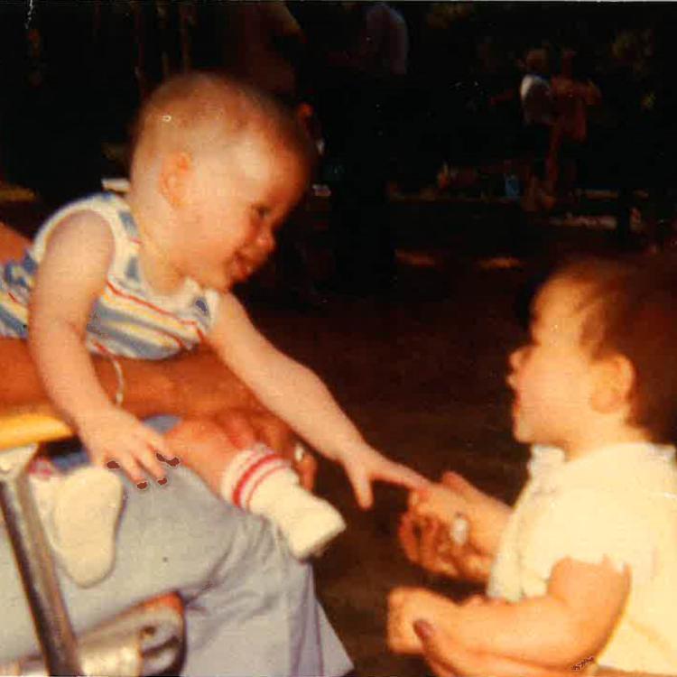 baby boy on lap reaches for little girl