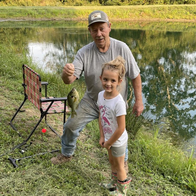 man holding a fish for a little girl