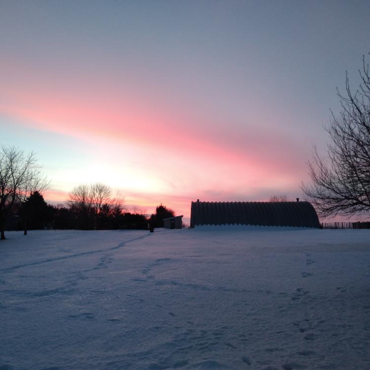 snowy field in front of building and sunset