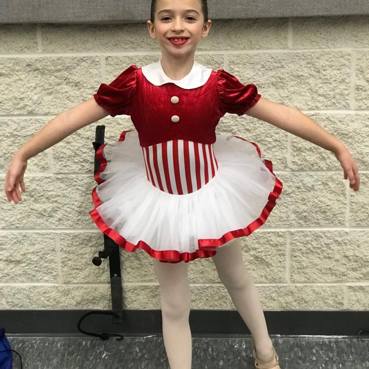 Young girl posing in dance costume with red-and-white striped body and red-trimmed white tutu