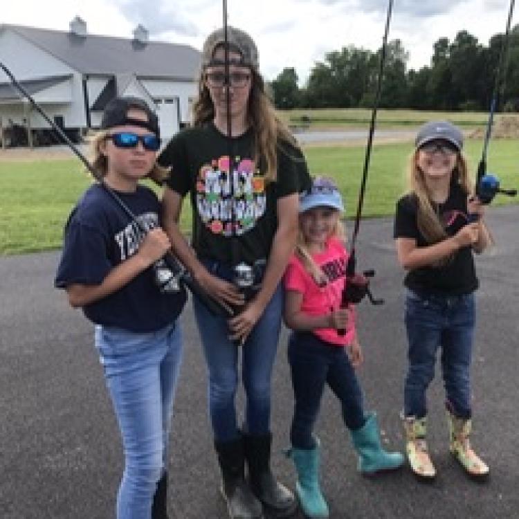 four kids holding fishing poles