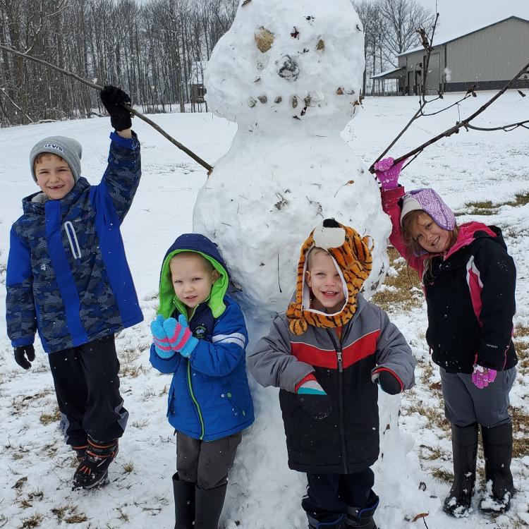 four children posing with giant snowman