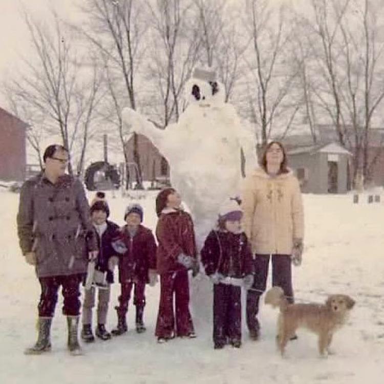 Family and dog around a giant snowman