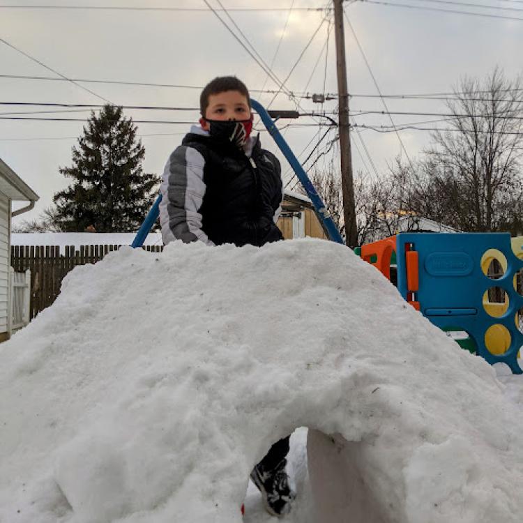 boy sitting on snow mound above tunnel