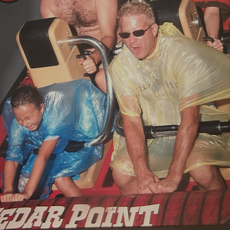 man and child in ponchos on roller coaster