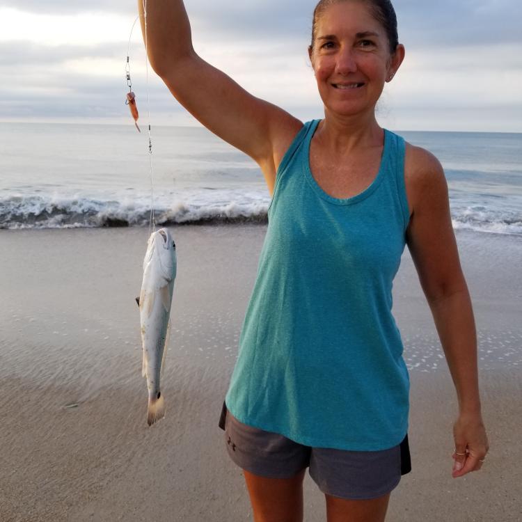 woman smiling while holding up a fish