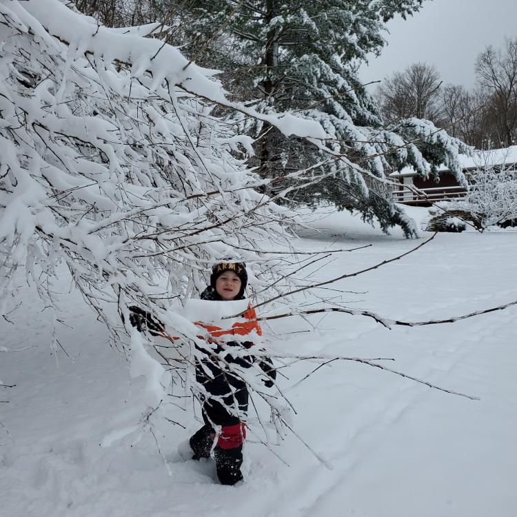 Boy next to snow-covered tree