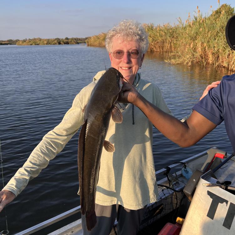 Woman smiling while a guide holds her fish