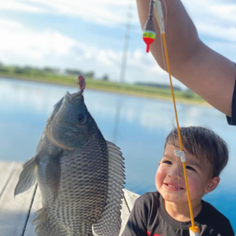 boy smiling while holding a fish