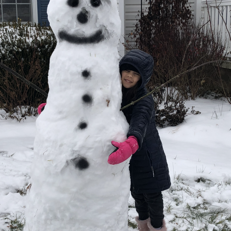 little girl hugging tall snowman