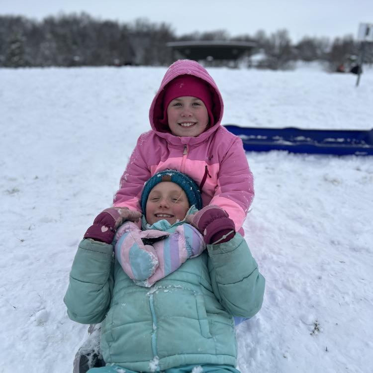 two girls on sled in snow