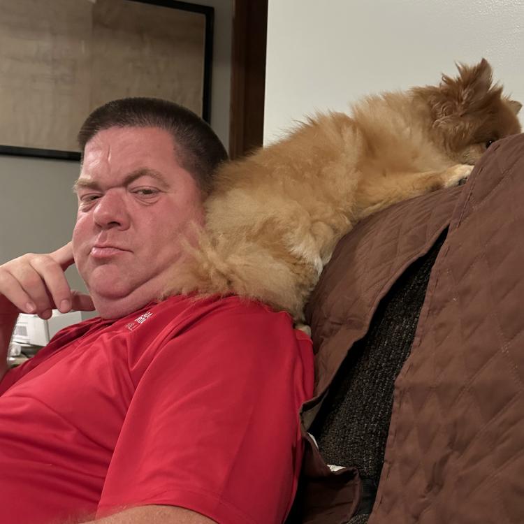man on couch with dog on shoulder
