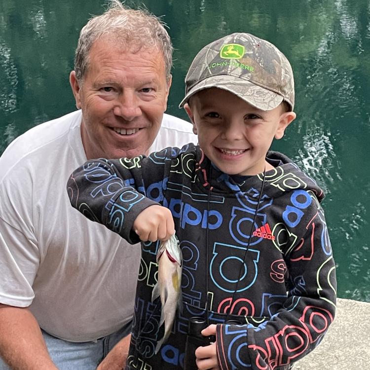 little boy and his grandpa holding a fish