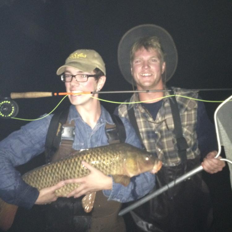 two boys smiling holding a large fish