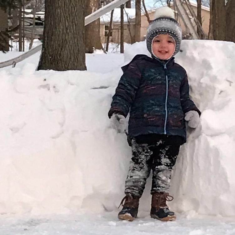 boy standing in front of snow fort