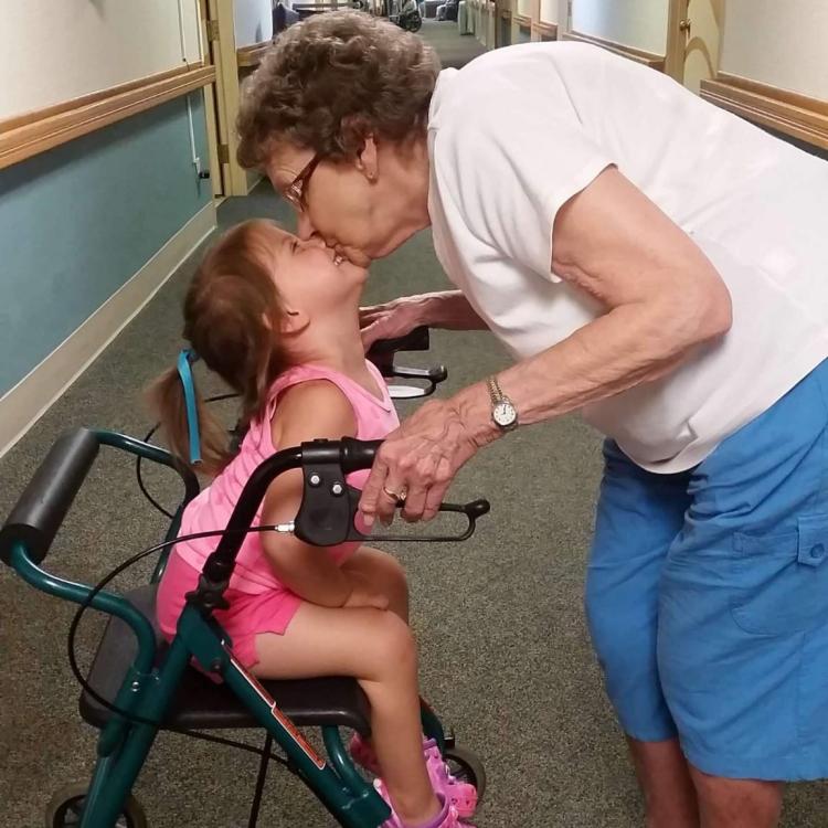 woman leaning down to kiss little girl