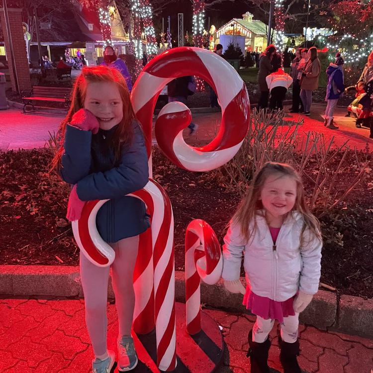 Two girls next to large plastic candy canes outdoors