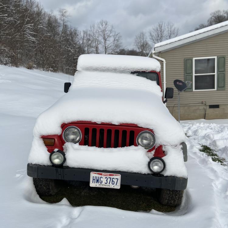 Front of red Jeep covered in snow