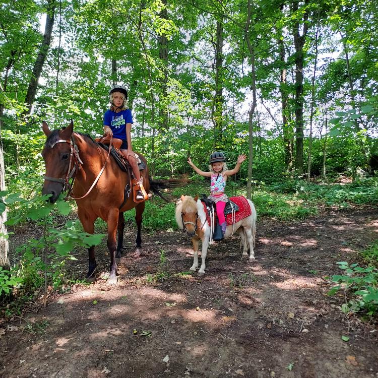 children on horseback on a wooded trail