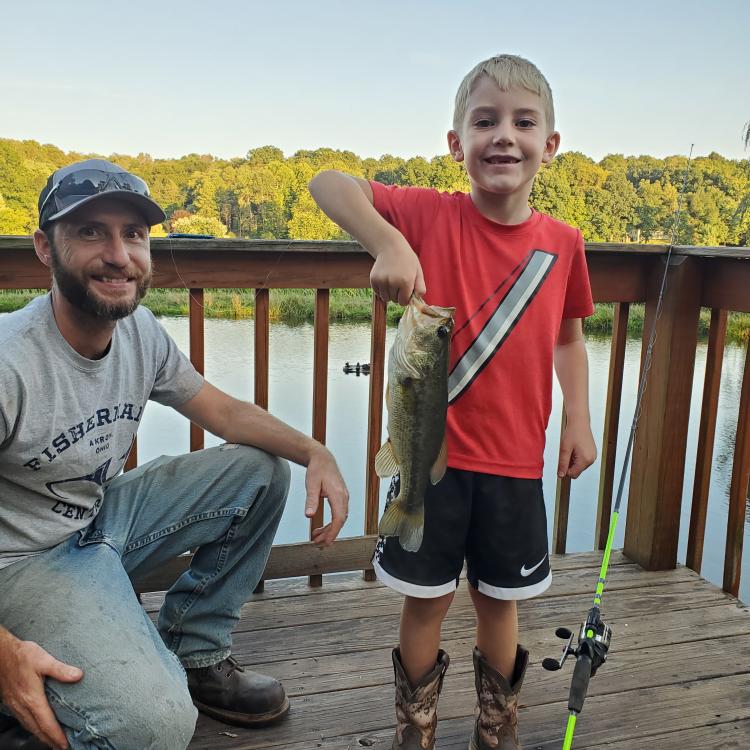 smiling boy with his dad holding a fish