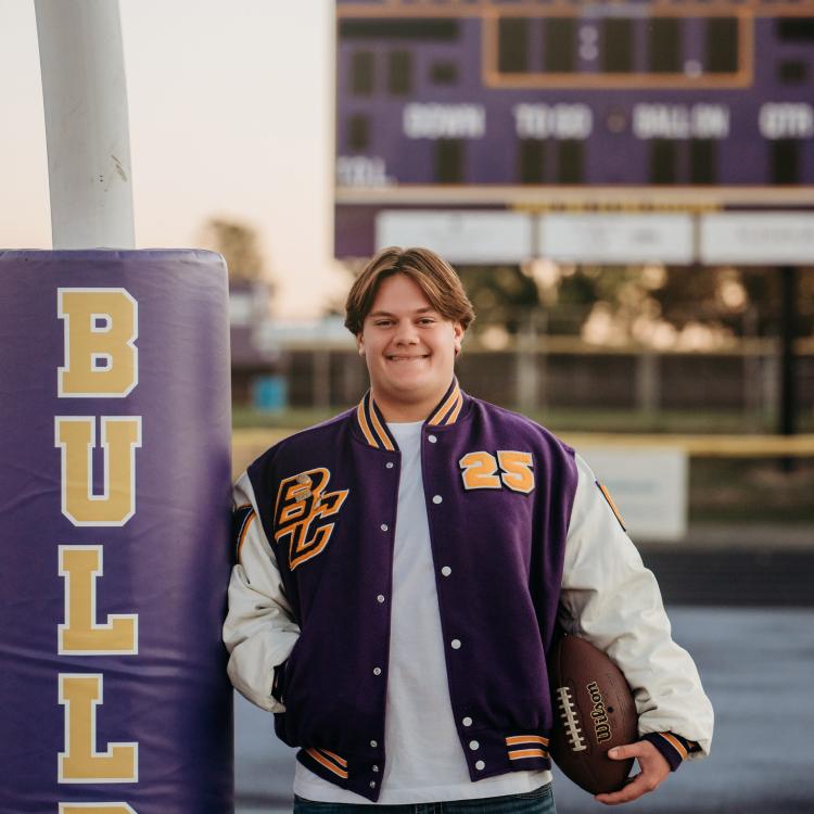 young man in letter jacket holding a football