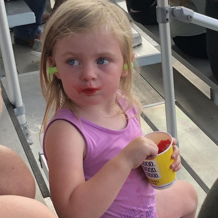 Little girl eating red shaved ice from a cup