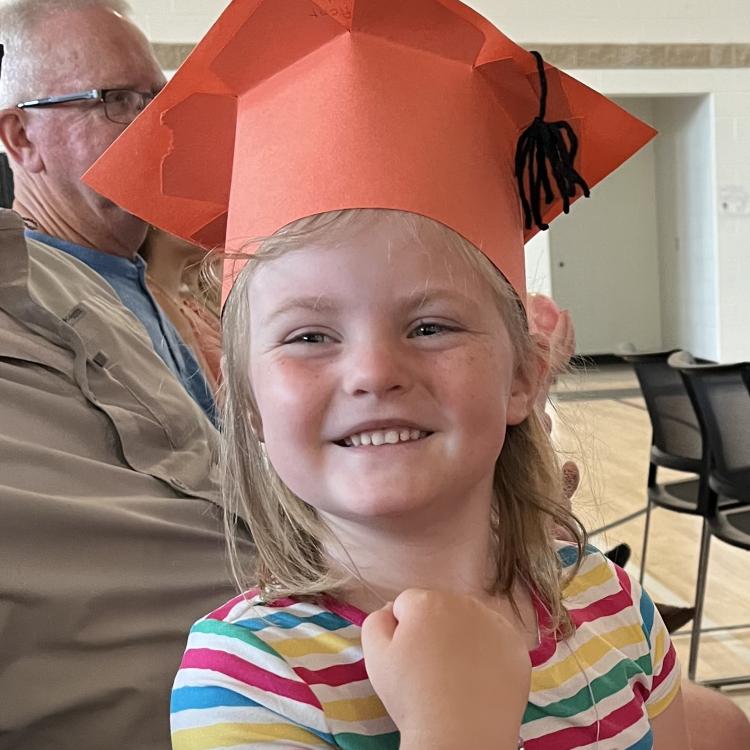 little girl in orange graduation cap