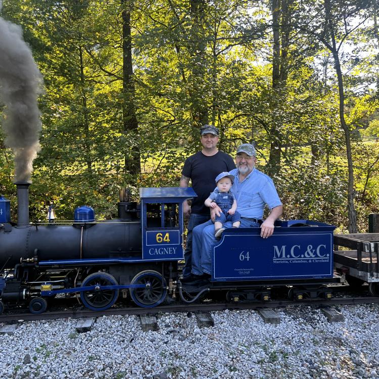 little boy with two men on miniature train