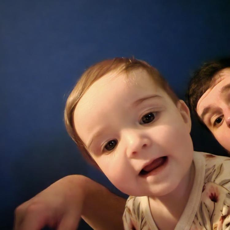 baby looking into camera, man in back