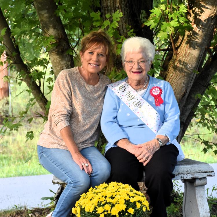 two women on bench in front of tree