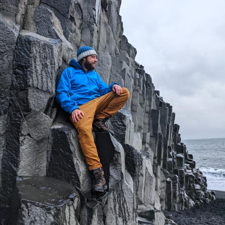 man on black stone cliff