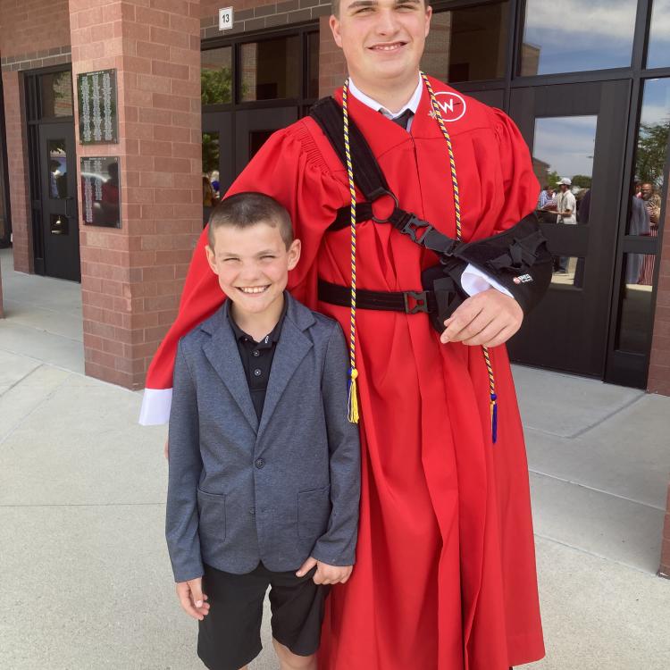 little boy with young man in red graduation gown