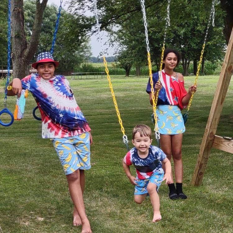 four kids in patriotic clothes on swings