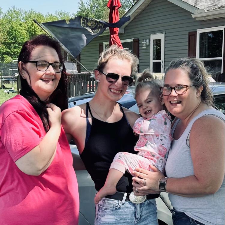 three women and a baby smiling outside