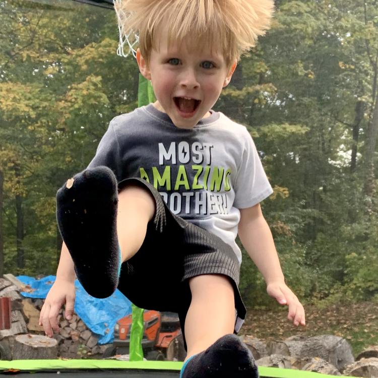 young boy on trampoline with hair flying