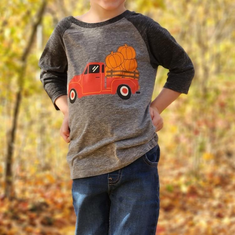 little boy standing in front of fall trees and leaves
