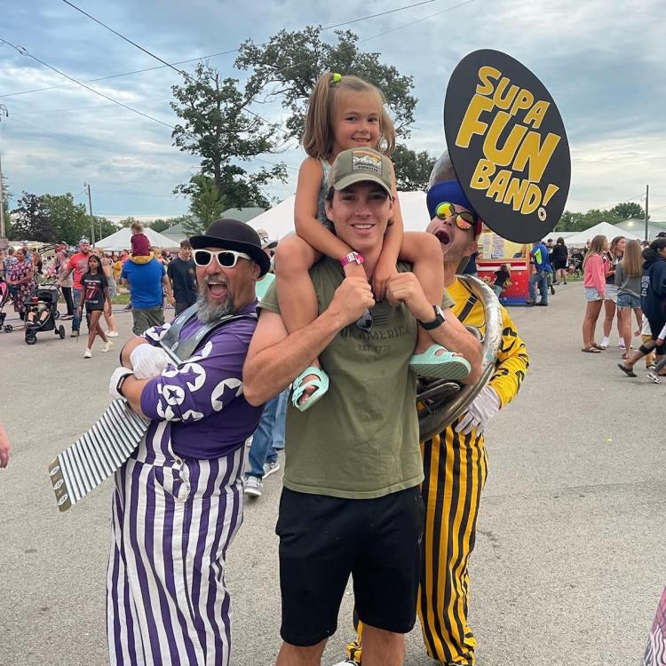 little girl on man's shoulders, with clowns