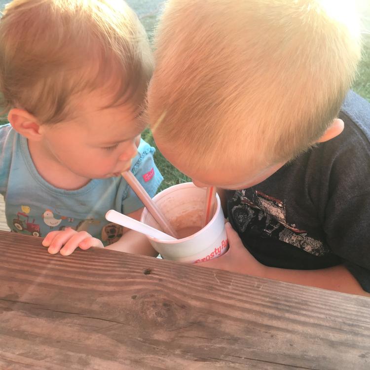 Toddler and baby sip milkshake through straws