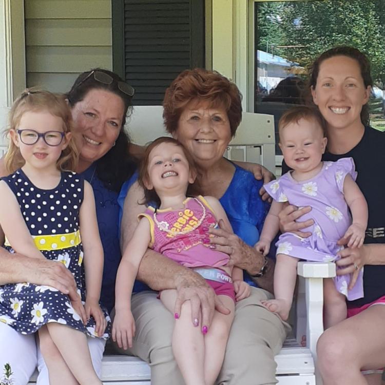 three women and three little girls on a porch