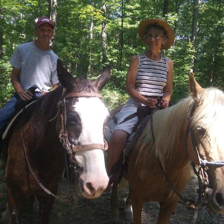 Man and woman on horses in woods