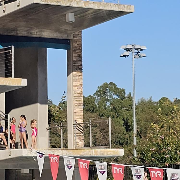 Girl jumps off high dive platform, touching her toes