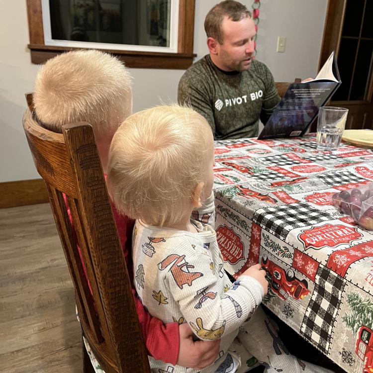 man reading to two children 