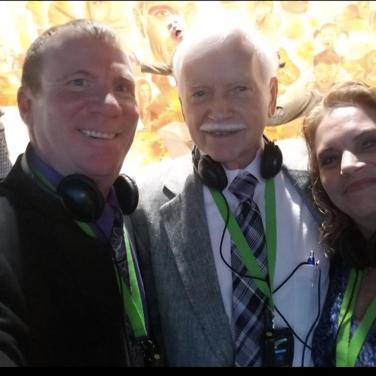 two men and a woman with headphones around their necks