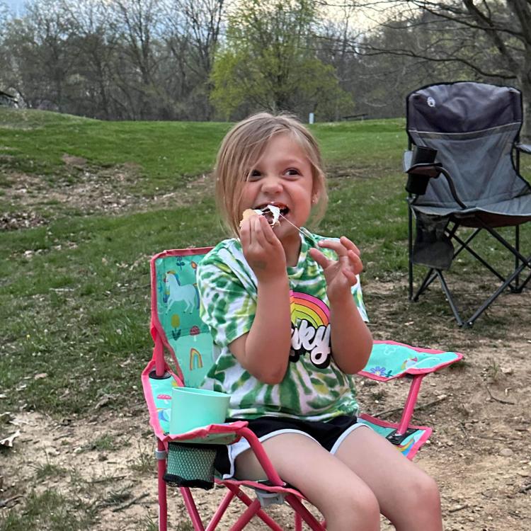 smiling girl bites into a s'more