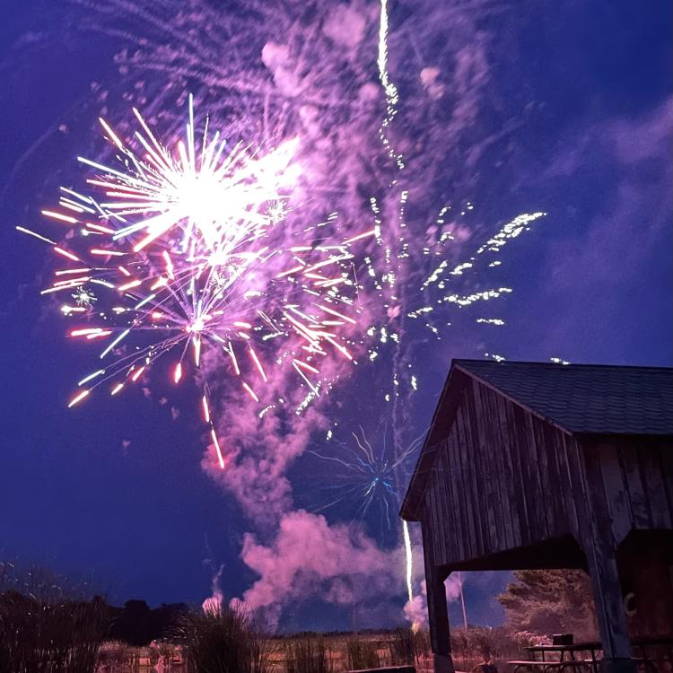 Barn silhouette in front of night sky with fireworks