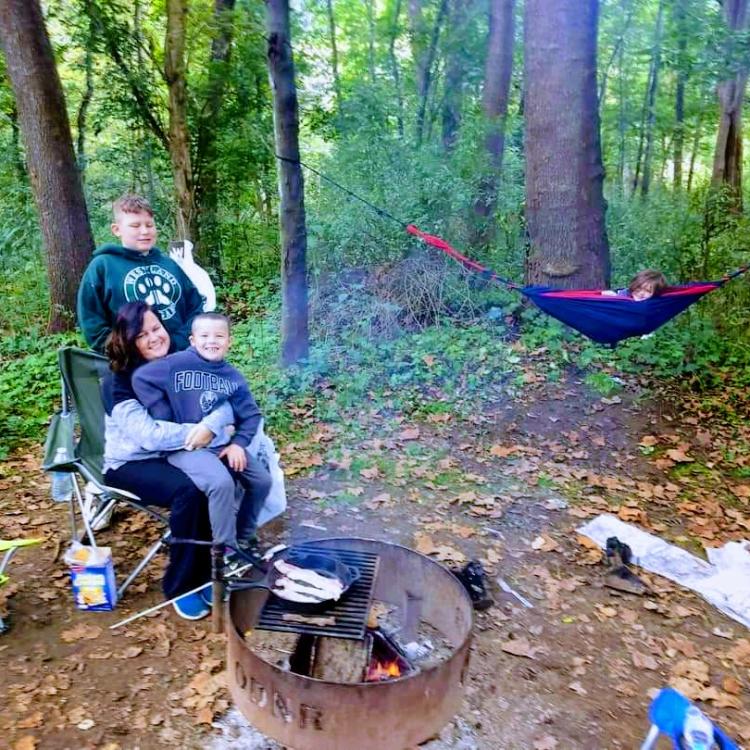 woman and three children by campfire